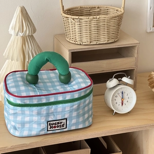 Detail of blue gingham cosmetic bag featuring green top handles and Lucky House label