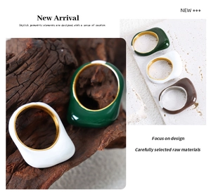 Detail of wide geometric enamel rings in green, ivory and brown with gold plating