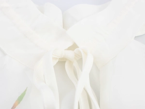 Détail du haut dos nu blanc avec nœud papillon élégant et texture en mousseline fine