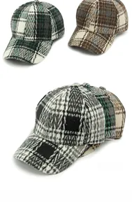 Detailed view of three plaid baseball caps in green, brown, and black wool patterns
