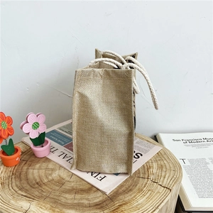 Eco-friendly jute bear lunch bag with white cotton rope handles on vintage background