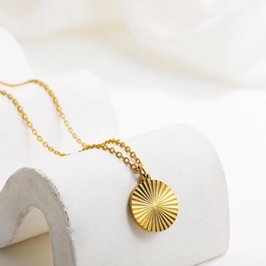 Macro view of 18k gold sunburst pleated circular pendant on a classic O-chain