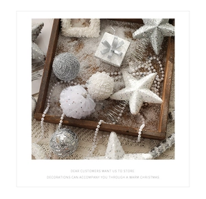 Silver and white glitter Christmas ornaments in a rustic wooden tray with snow details