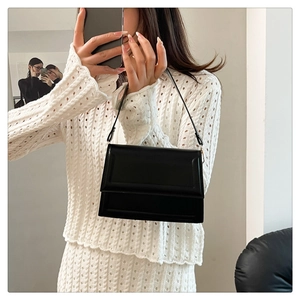Chic black leather rectangular shoulder bag shown on model with white knit sweater