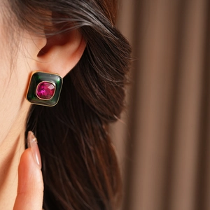 Close-up of vintage square emerald enamel stud earring with a ruby-colored center gemstone