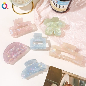 Flat lay of six translucent acrylic hair claws in assorted floral and geometric shapes