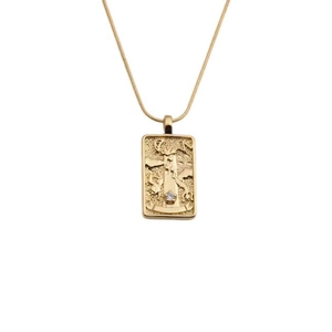 Detailed close-up of a golden tarot-style embossed pendant with a sparkling clear stone