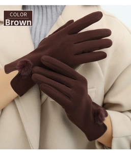 Close-up of coffee brown winter gloves featuring decorative fur pom-pom at the wrist
