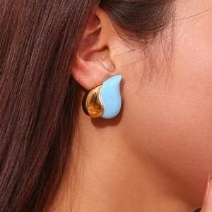 Close-up of teardrop earrings with gold metal and light blue enamel on a model