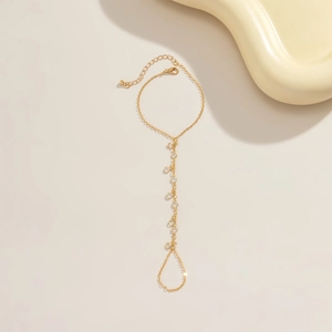 Detail of gold metal hand chain with sparkling crystals on minimalist beach slave bracelet