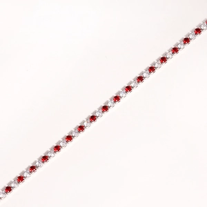 Detail view of a silver bracelet featuring alternating red and clear zircon stones