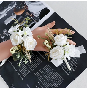 Detailed set of white silk rose boutonniere and wrist corsage for wedding guests