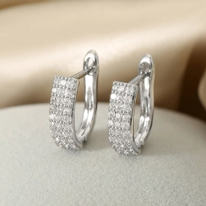 Elegant silver hoop earrings with clear cubic zirconia diamonds on a soft grey surface