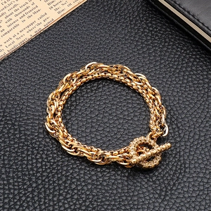 Detailansicht des goldenen mehrlagigen Kettenarmbands mit OT-Verschluss auf schwarzem Leder