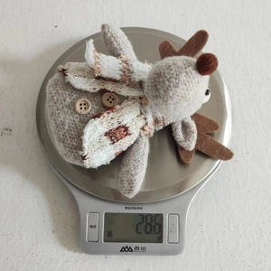 Detail shot of a plush reindeer ornament on a digital scale weighing 28.6g for Christmas