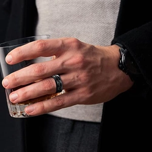 Men's matte black titanium steel spinner ring with relief chain texture on hand