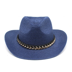 Detalle de un sombrero vaquero de paja azul con una cadena decorativa de metal dorado