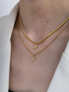Close-up of layered gold initial R necklaces with zircon snake and link chains