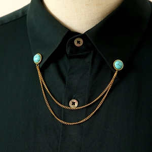 Dettaglio di una catena da colletto dorata vintage con pietre turchesi su camicia nera