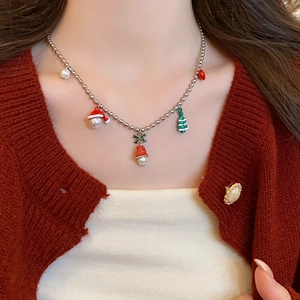 Close-up of a Christmas themed necklace with red bells and green tree on a red sweater