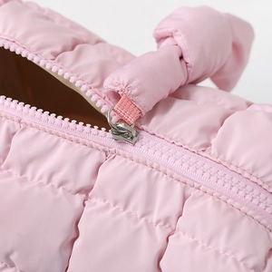 Detail view of pink quilted cosmetic bag with plastic zipper and knotted handle