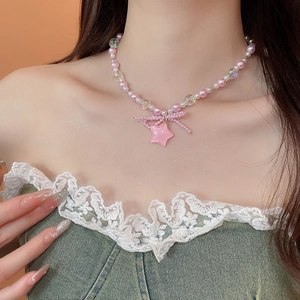 Close-up of pink star pendant necklace with beaded bow and faux pearls on neck