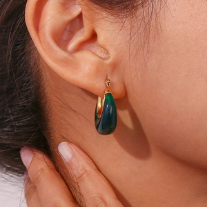 Close-up of a green teardrop earring with gold finish worn on a female model