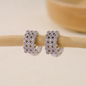 Close-up of silver hoop earrings with sparkling cubic zirconia on a wooden display