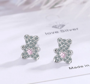 Macro shot of teddy bear stud earrings with white zircons and pink heart gemstones