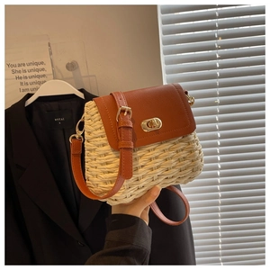 Detail of handmade woven crossbody bag with brown leather flap and golden metal clasp