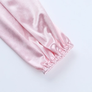 Détail d'une manche de robe en satin rose avec poignet élastique et texture soyeuse