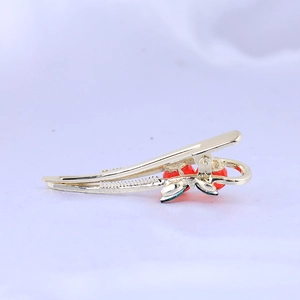 Golden duckbill hair clip with red rhinestone cherries shown in a side-angle view