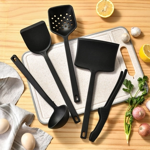 5-piece black heat-resistant silicone kitchen utensil set on a wooden table with ingredients