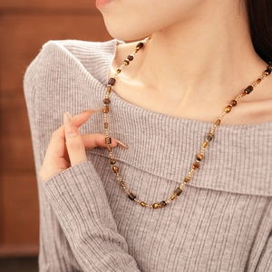 Close-up of brown and amber beaded necklace with gold accents on a grey sweater