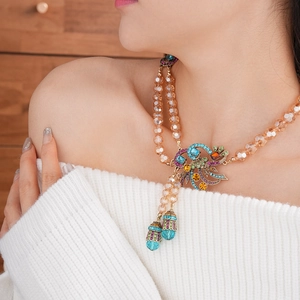 Close-up of a vintage peacock pendant necklace with colorful beads on a fashion model
