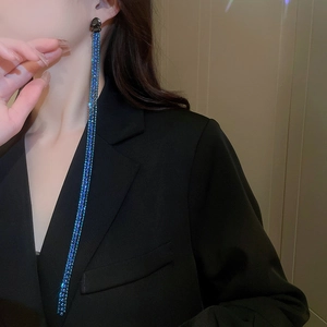 Close-up of long blue tassel earrings with sparkling rhinestones on a fashion model