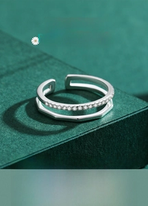 Macro detail of double-layer s925 silver ring with zircon inlay on a green background