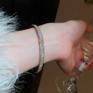 Detail of elegant gold bangle with pavé-set zircons worn against a white fur sleeve
