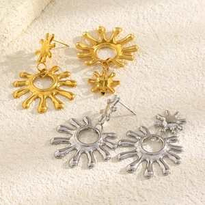 Vue détaillée des boucles d'oreilles soleil en or et argent sur surface en pierre