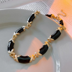 Détail du collier vintage en émail noir avec maillons croisés dorés sur plat