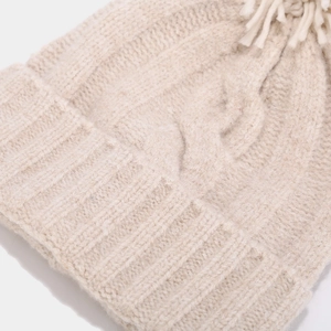 Close-up of beige cable knit beanie showing thick wool texture and ribbed cuff detail