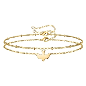 Detail view of a gold double-layer anklet with bird pendant and zircon stone accents