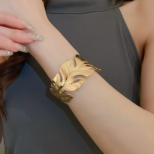 Detail shot of a golden tropical monstera leaf cuff bracelet on a female wrist