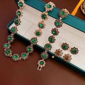 Detailed view of vintage gold-plated jewelry set with emerald stones in a velvet box