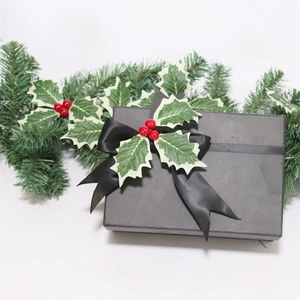 Close-up of elegant black Christmas gift box with silk ribbon and red berry holly decor
