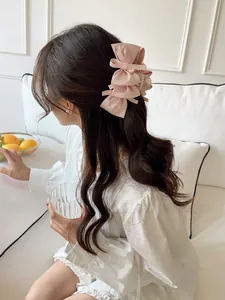 Detail of a pink multi-layer satin bow hair claw clip worn on a woman's head