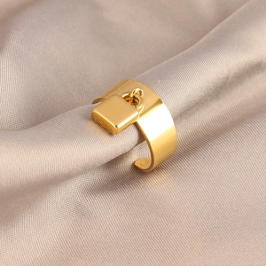 Polished gold stainless steel wide open ring with a dangling padlock charm on silk