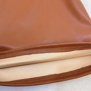 Makroaufnahme von braunen Lederhosen mit präzisen Nähten und gelbem Stofffutter im Detail