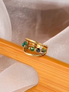 Detail of gold-plated multi-layer ring with textured finish and green gemstone beads