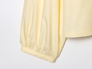 Detailed close-up of pleated cuff stitching on pale yellow poplin cotton shirt